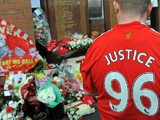 A Liverpool football club supporter looks at floral tributes and memorabilia ahead of a memorial service to mark the twentieth anniversary of the Hillsborough disaster at Anfield in Liverpool, north-west England on April 15, 2009