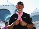 Darren Clarke of Northern Ireland poses with a pink scarf supporting breast cancer awareness before teeing off in the Challenge Match ahead of the Omega Dubai Desert Classic on January 27, 2015